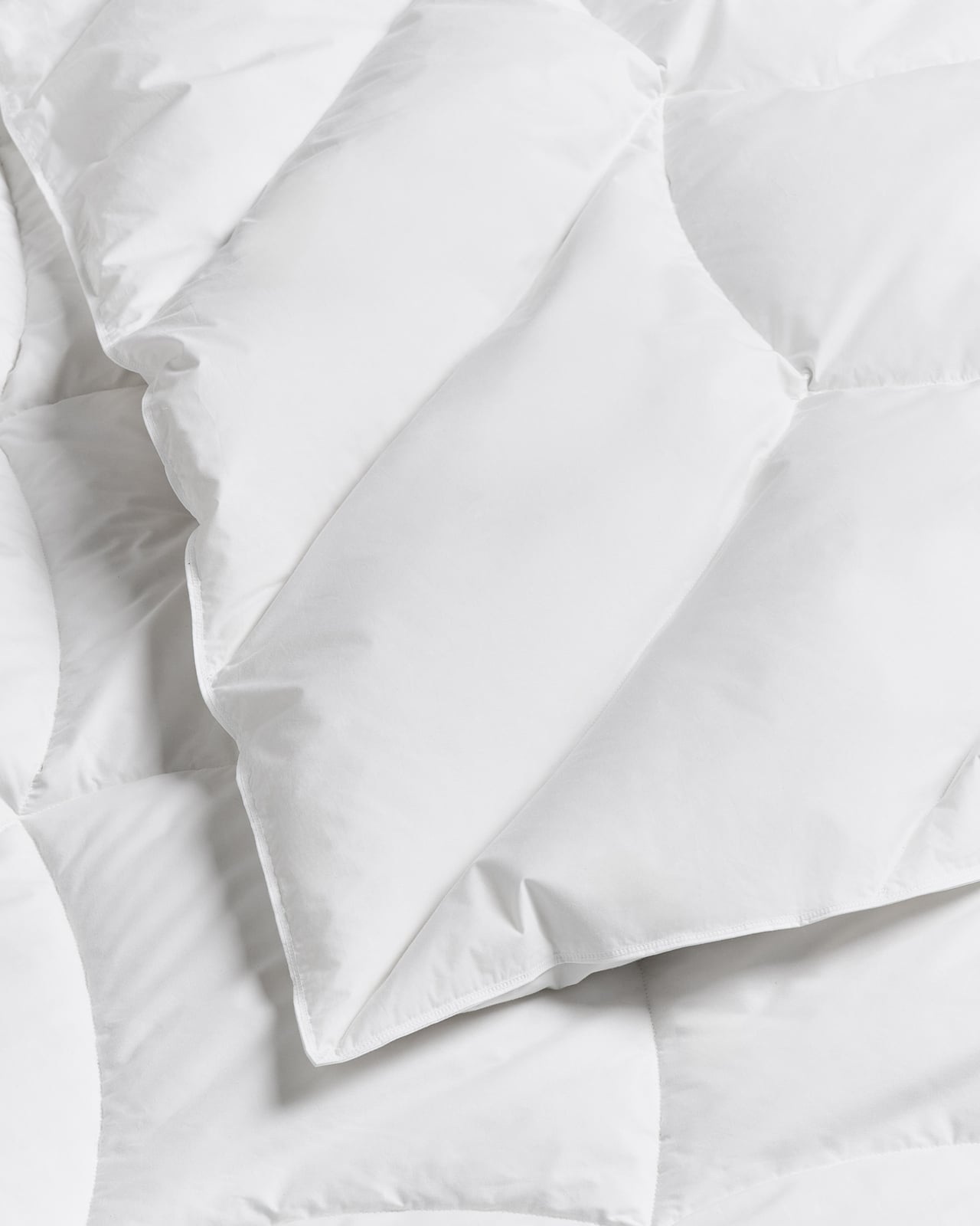 Down and Feather Duvet – Medium in White, a white cotton duvet with a stitched grid pattern, folded neatly.