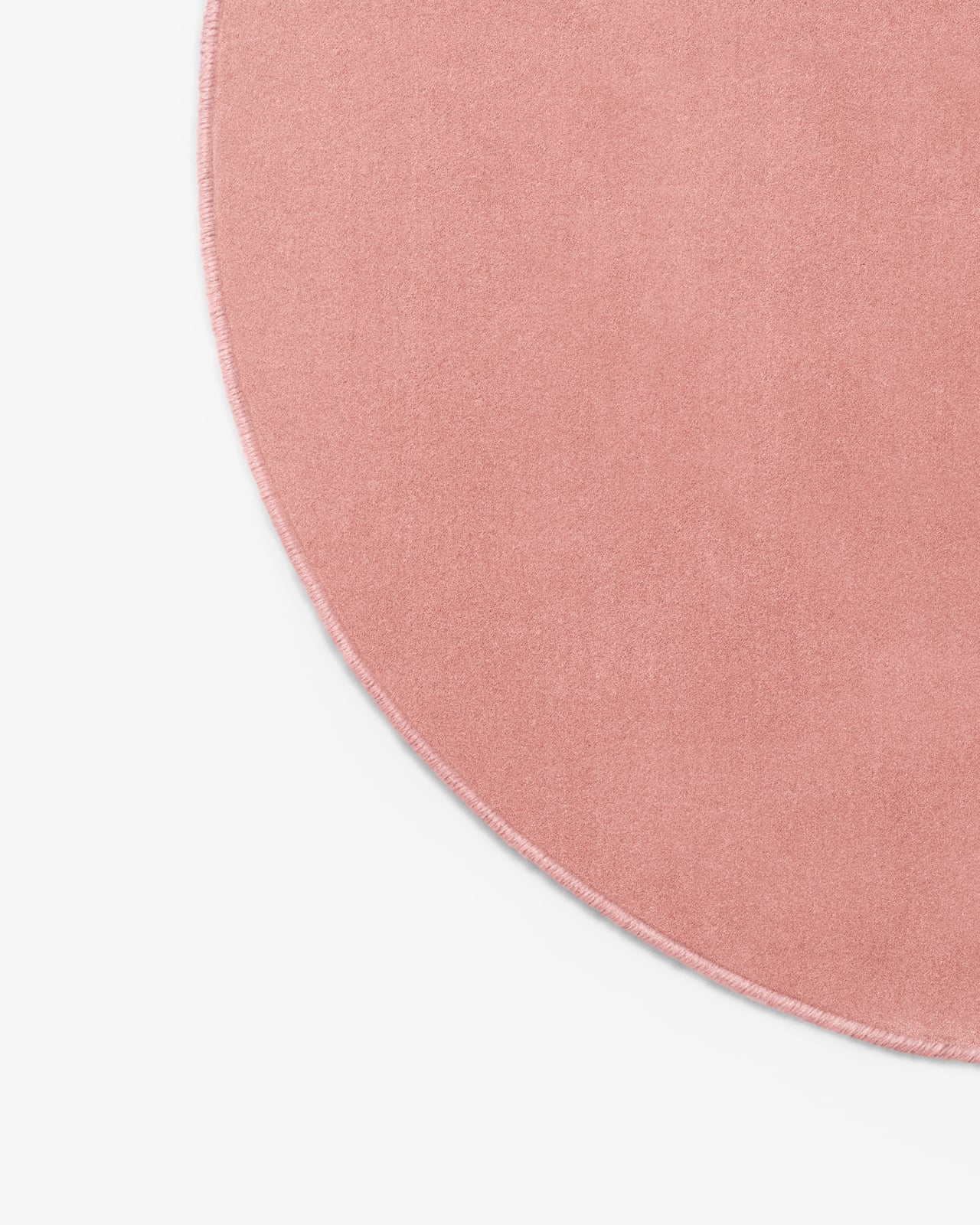 Close-up of Grand - Sakura Pink - Custom Size, showing smooth cut pile and a serged edge.