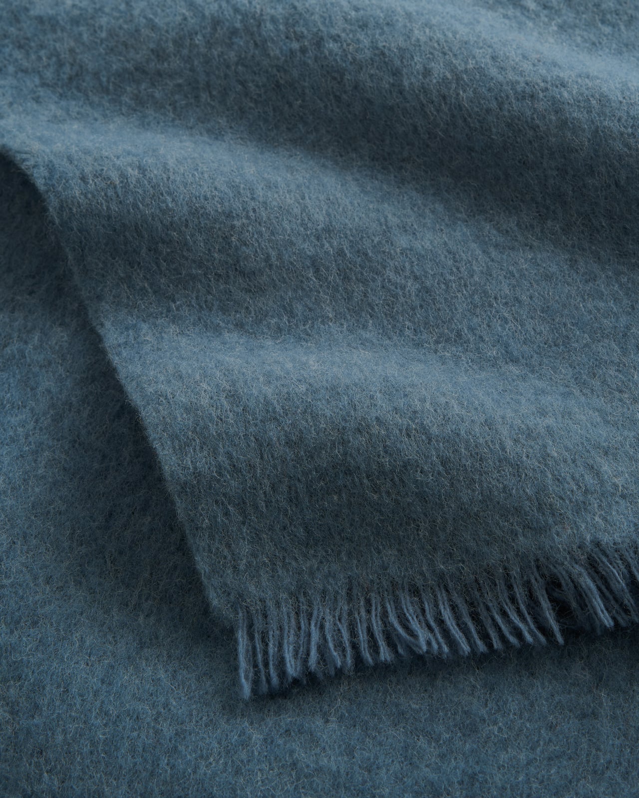 Solid Brushed Alpaca Throw in Slate Blue, ein denimblaues Wollplaid mit weicher Oberfläche und Fransen.