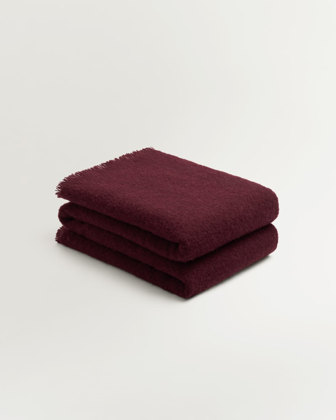 Solid Brushed Alpaca Throw in Deep Wine, a full-bodied red wool and alpaca throw with a brushed texture and delicate fringe.