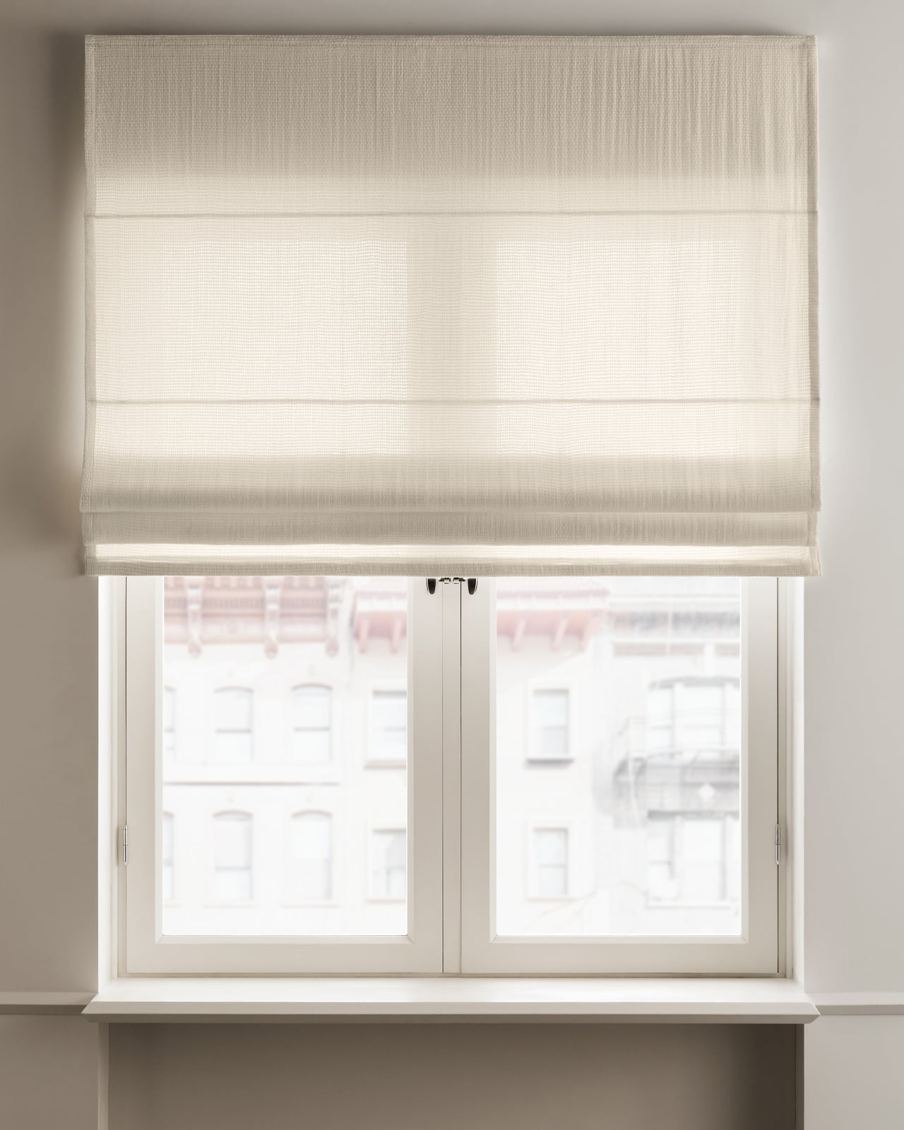 The Basket Weave Roman Shade in Perfect White on a window, highlighting its wool basket weave texture.