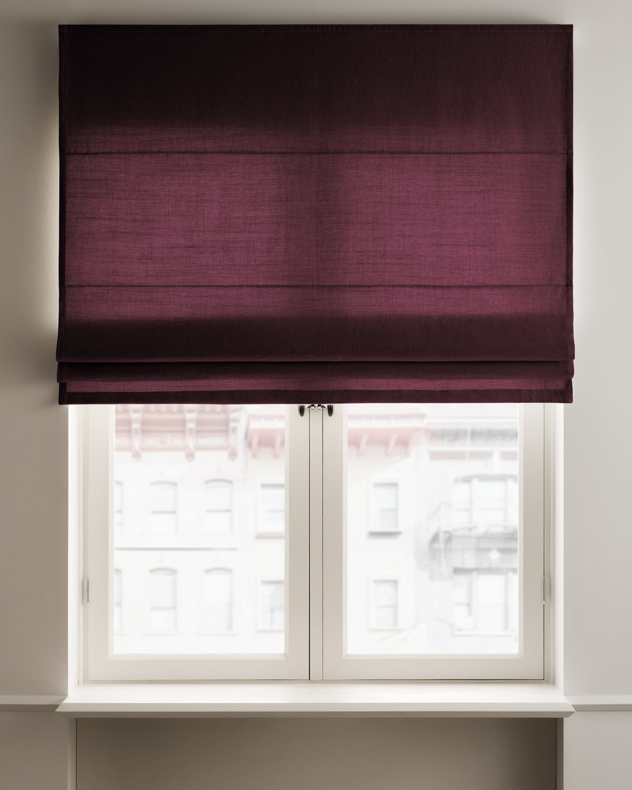 The Studio Linen Roman Shade - Blackout Lining - Deep Wine in a room, highlighting its linen weave and soft folds.