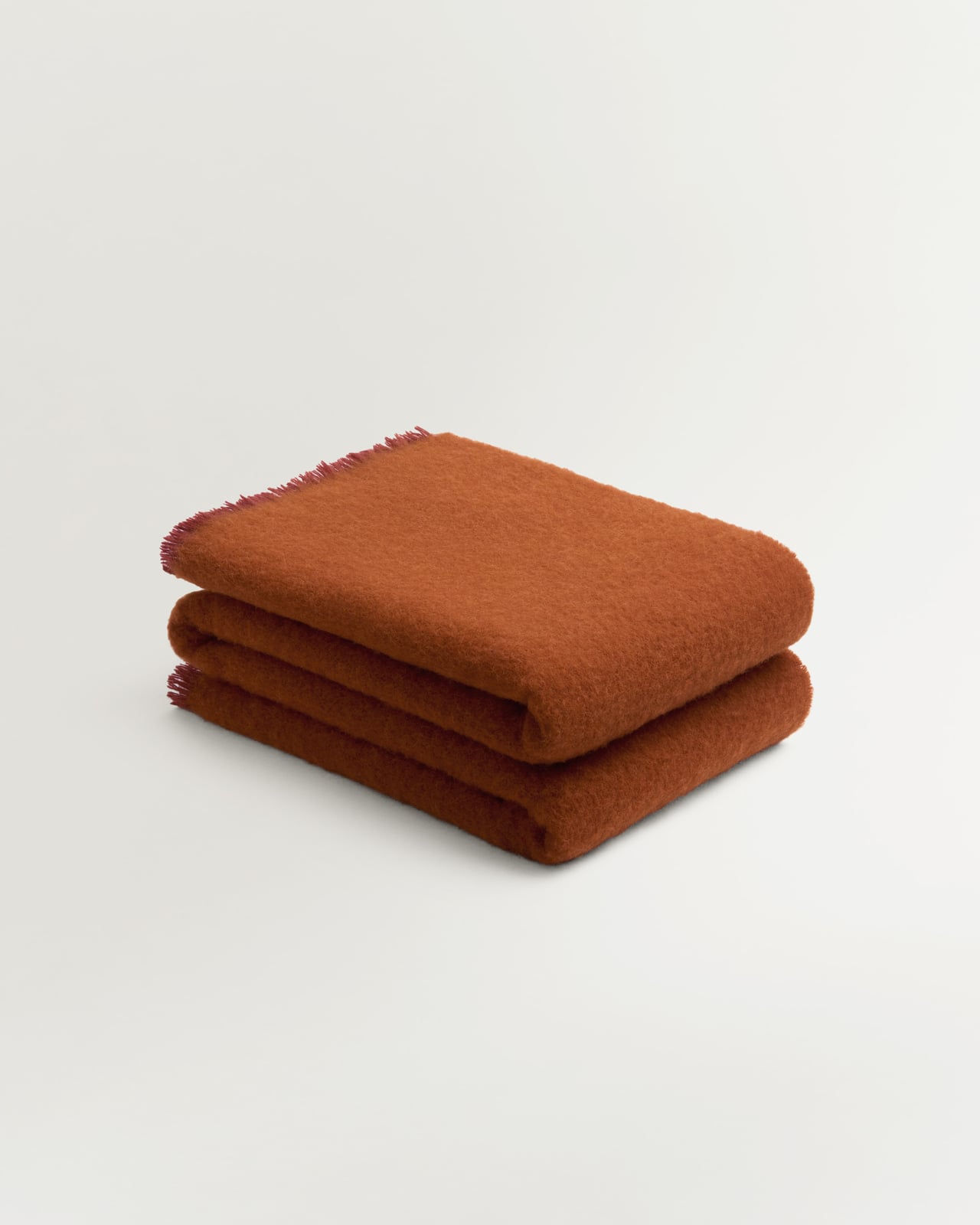 Solid Brushed Alpaca Throw in Burnt Orange, an earthy rust wool and alpaca throw with a brushed surface and delicate fringe.