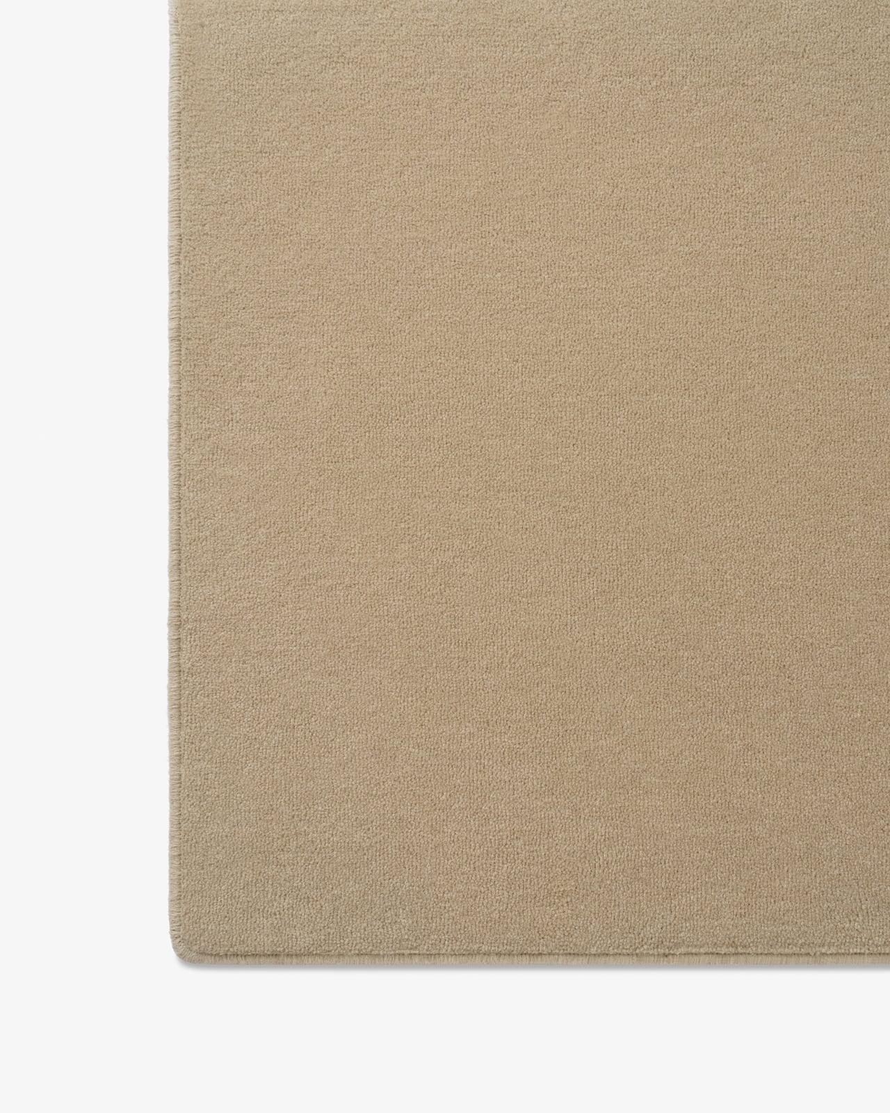 Close-up of the made-to-measure Avenue rug in Sand, showing its dense tufted cut pile and edge binding.